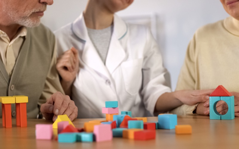 senior man woman combining color building blocks table dementia therapy