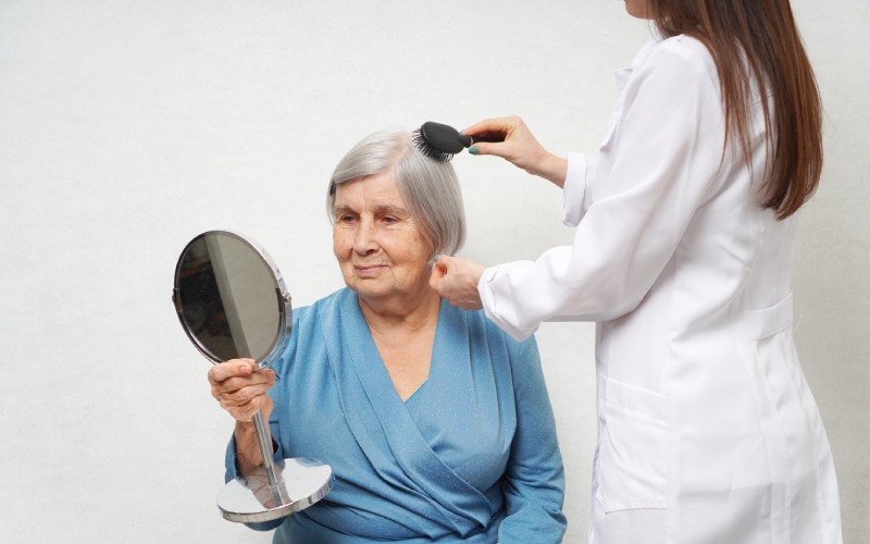 health visitor combing hair senior woman aged woman looking mirror