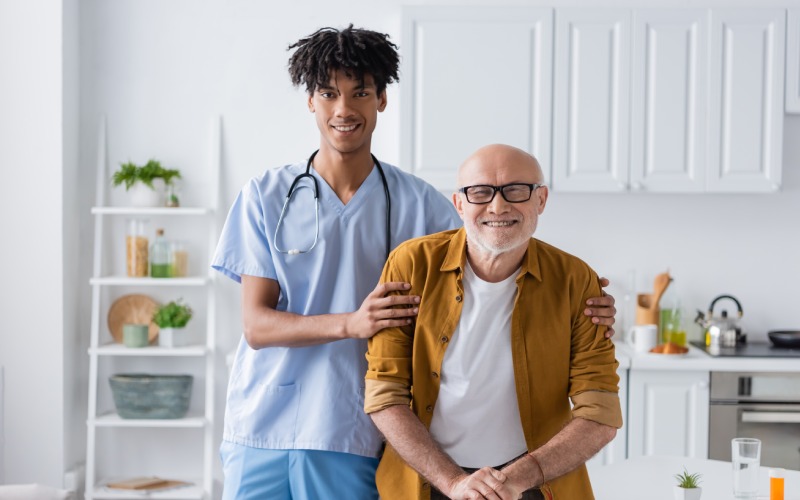 cheerful-african-american nurse hugging elderly patient walking cane home