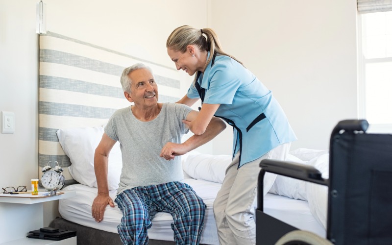 smiling nurse assisting senior man get bed caring nurse supporting